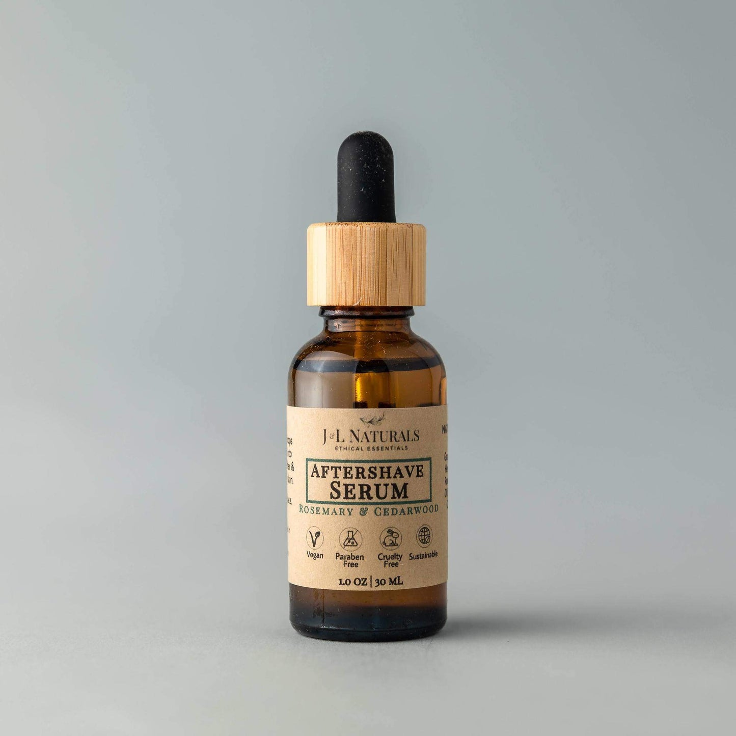 Bottle of J.L. Naturals Aftershave Serum on a gray background