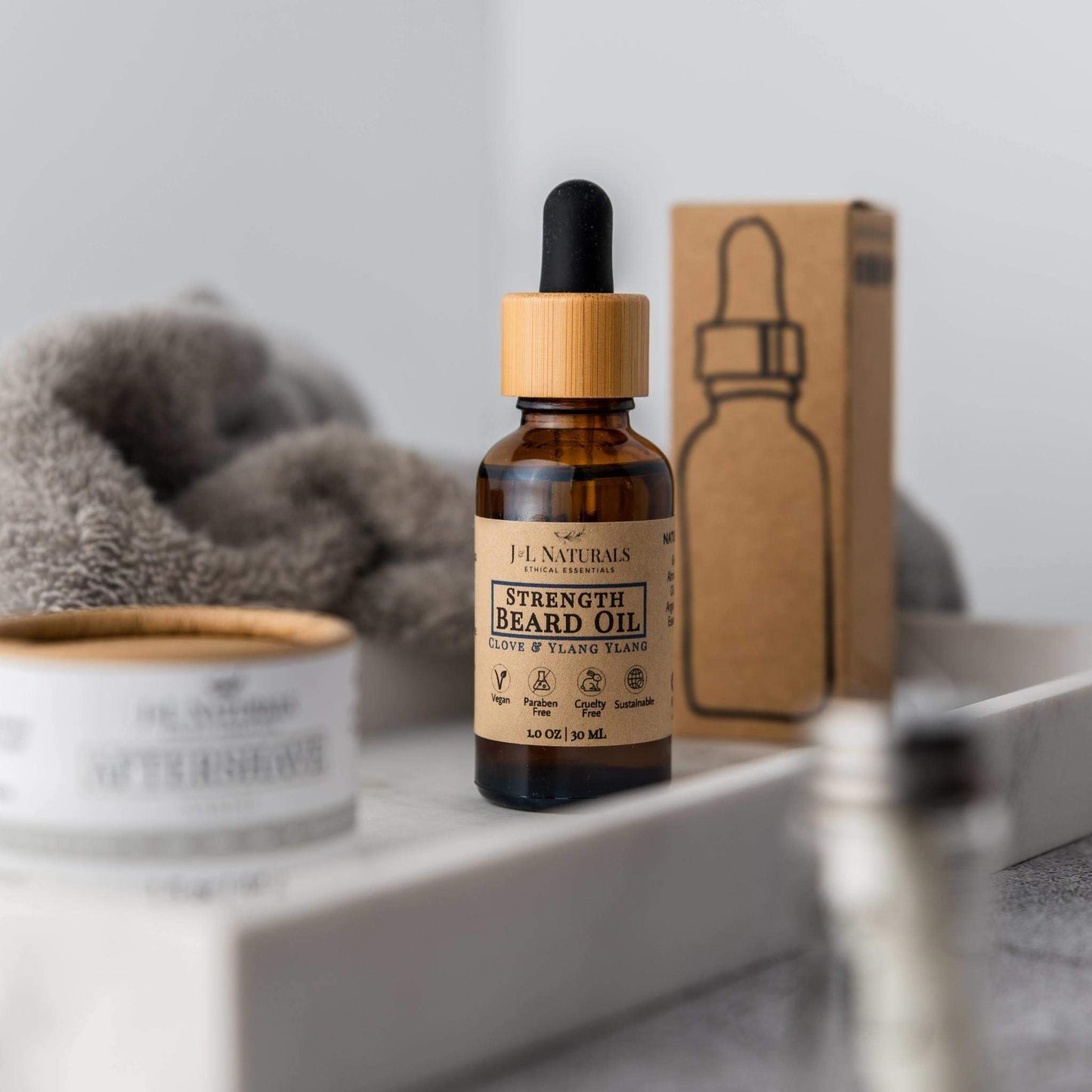 Bottle of strength beard oil with a dropper on a shelf with a box in the background.