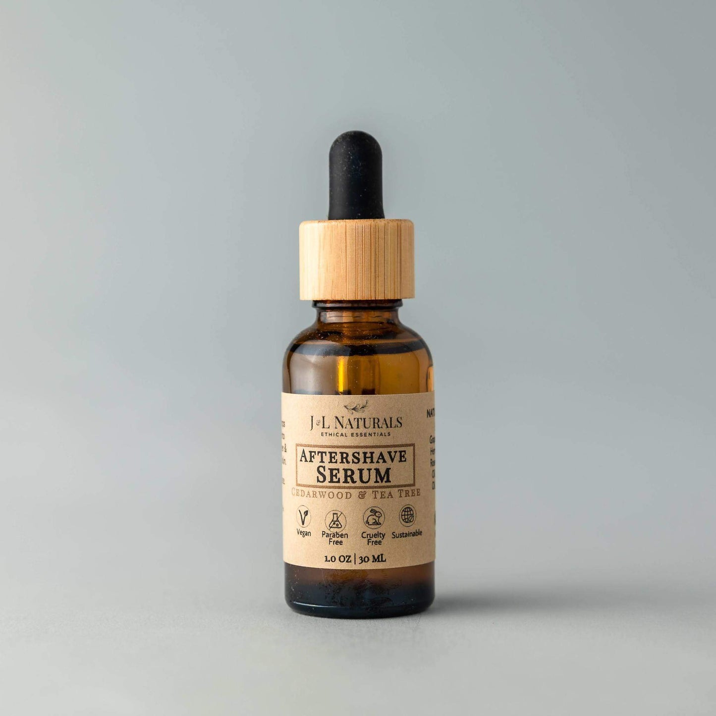 Bottle of J.L. Naturals aftershave serum with a dropper on a gray background