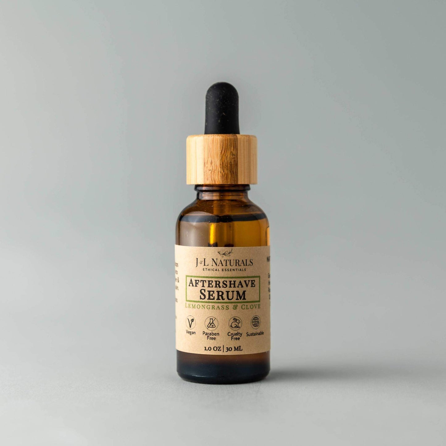 Bottle of J.L. Naturals Aftershave Serum with a dropper on a gray background