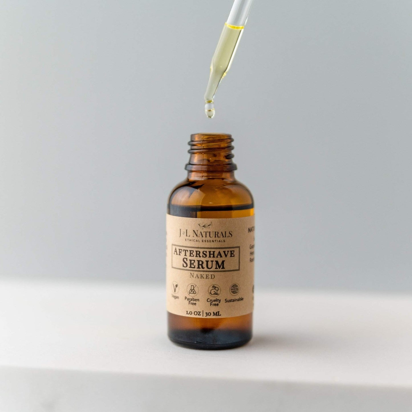 Aftershave serum bottle with dropper on a light gray background