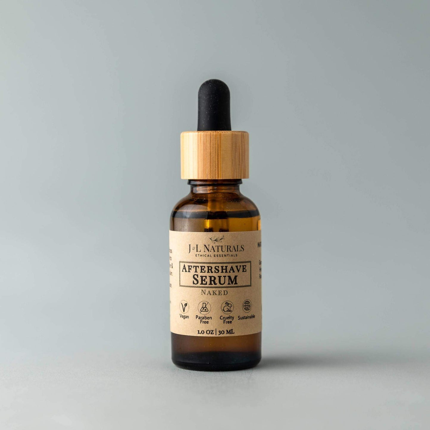 Bottle of J.L Naturals Aftershave Serum with wooden dropper on a gray background