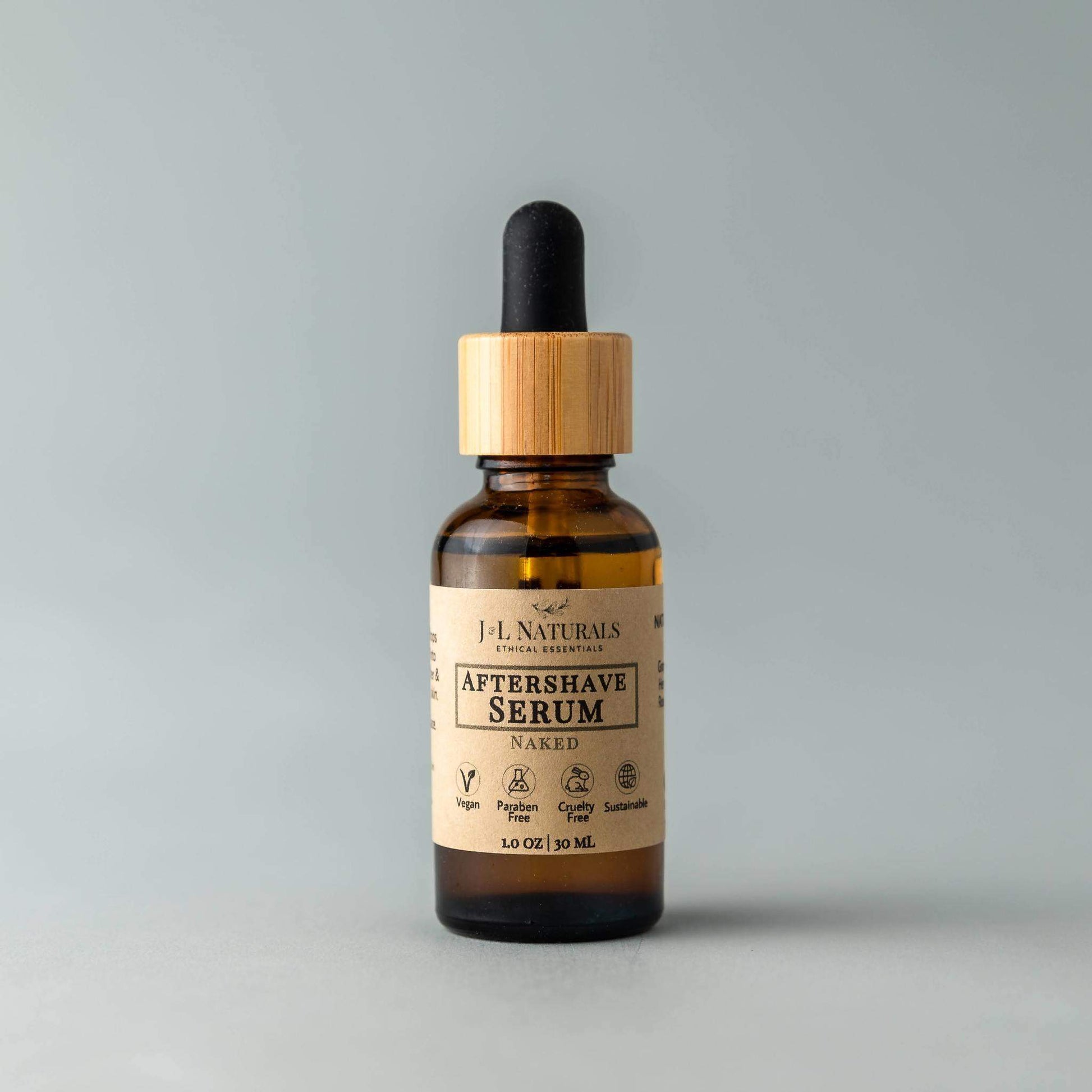Bottle of J.L Naturals Aftershave Serum with wooden dropper on a gray background