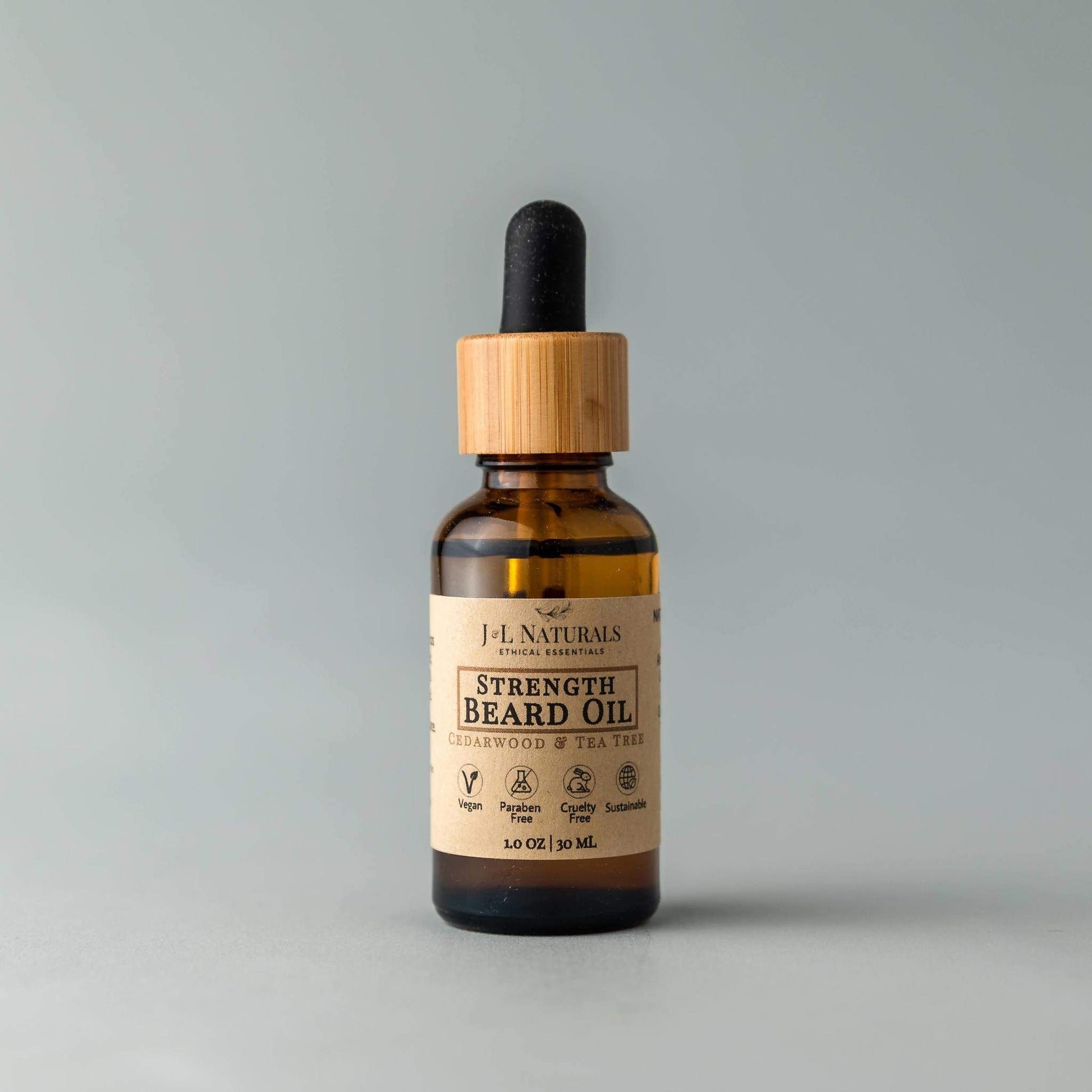 Bottle of H.L. Naturals Strength Beard Oil with wooden dropper on a gray background