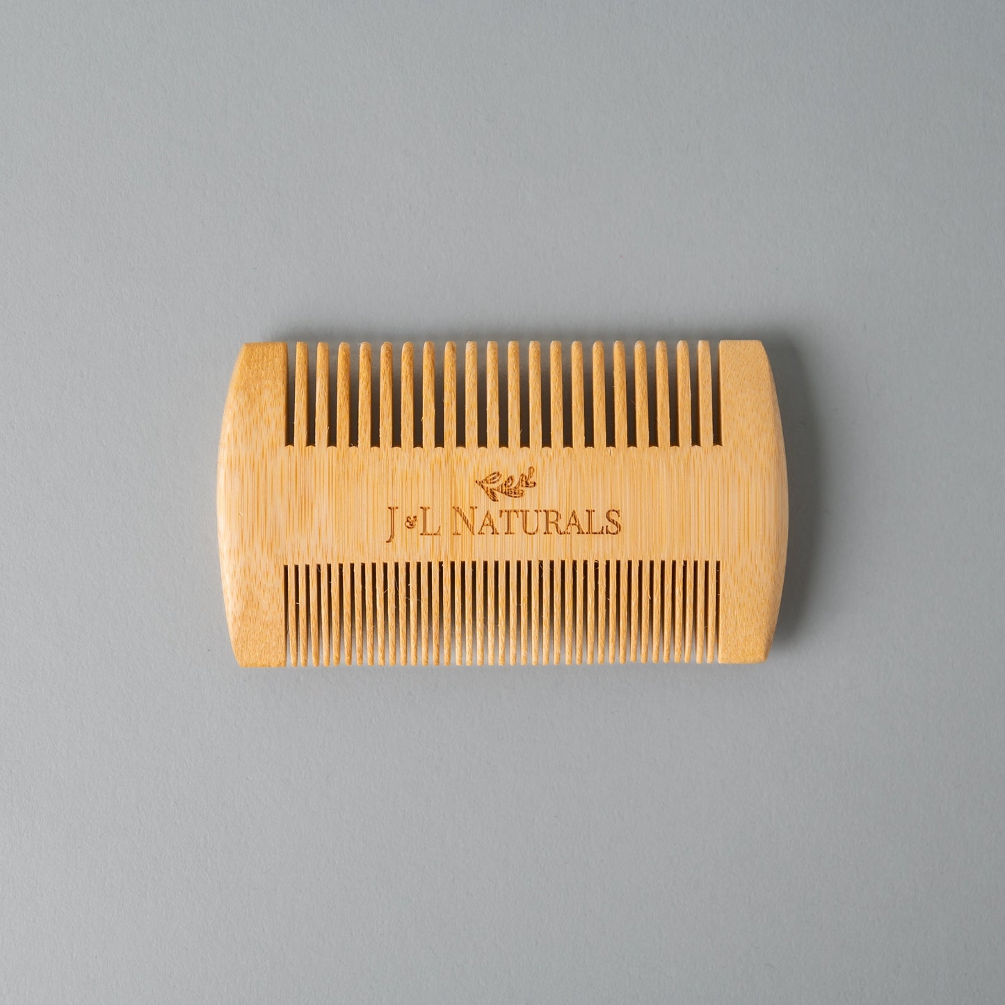Wooden comb with 'J&L Naturals' branding on a gray background