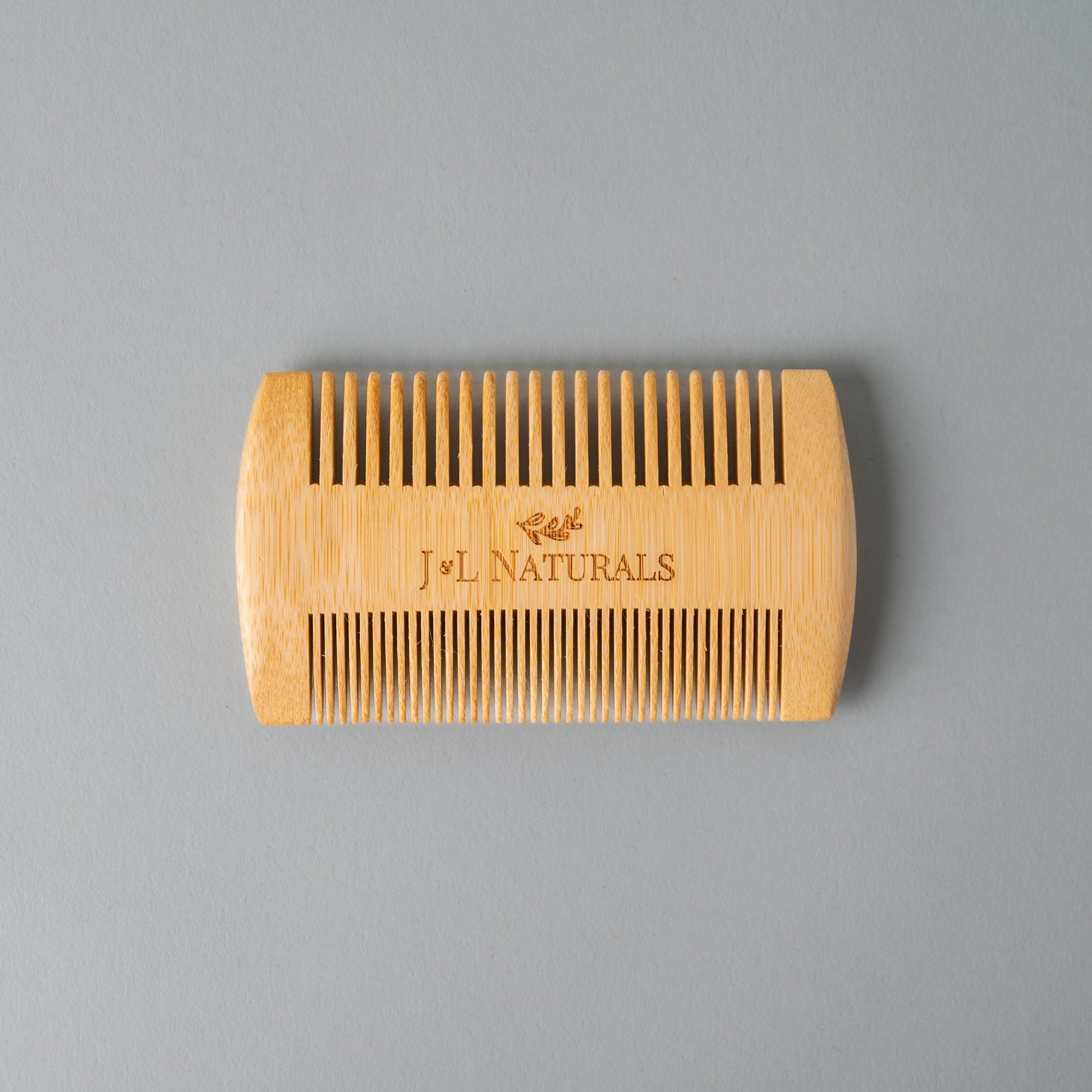 Wooden comb with 'J&L Naturals' branding on a gray background